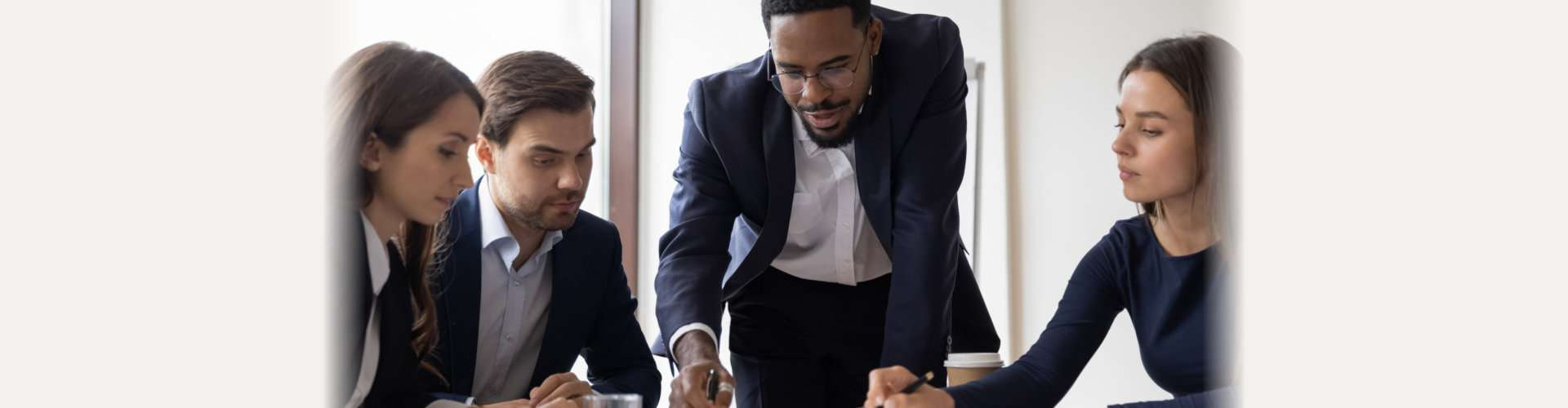 Confident African American businessman hold lead meeting with diverse colleagues in office. Multiracial businesspeople brainstorm discuss company financial paperwork at briefing. Teamwork concept.